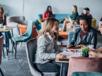 Three women sit at a table in a cafe.
