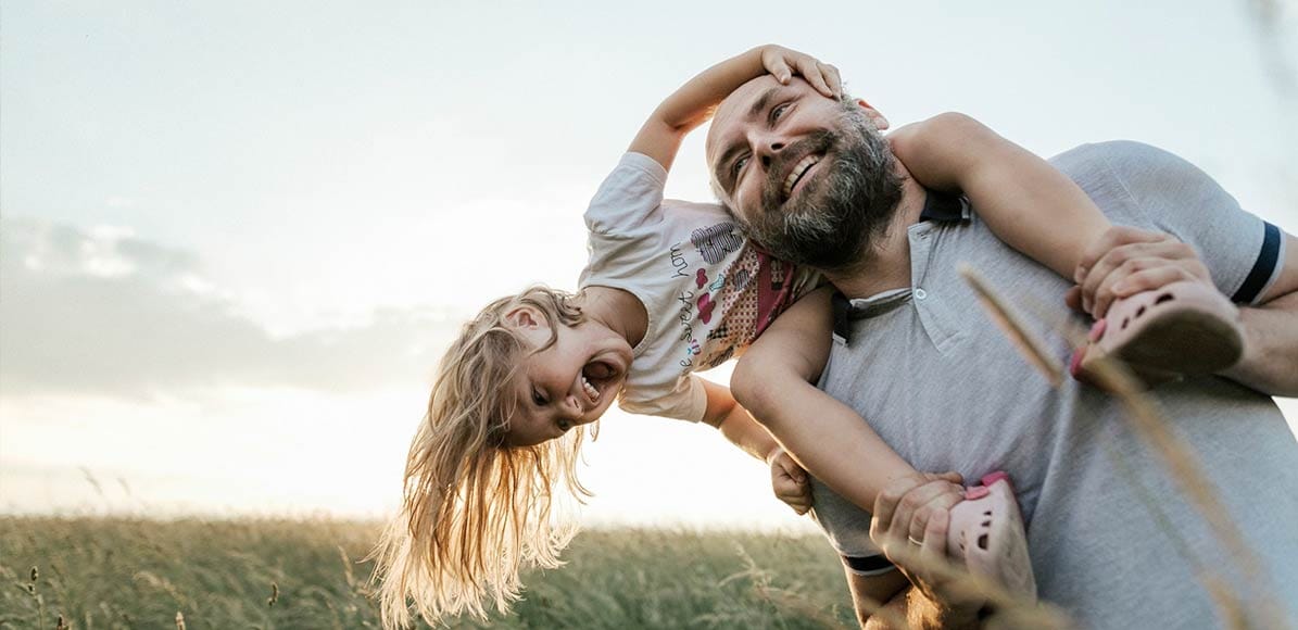 Man with daughter on his shoulders, playing outside